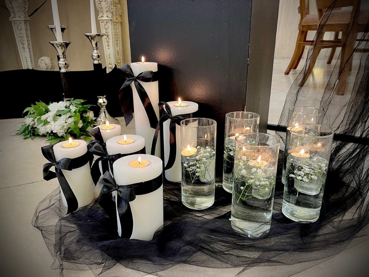 White pillar candles with black ribbons and floating candles in glass cylinders.