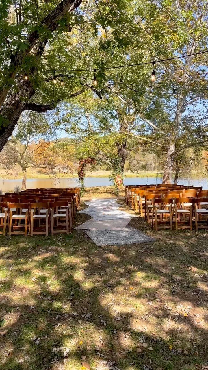 Light-colored rugs forming an aisle between wooden chairs at an outdoor wedding ceremony.
