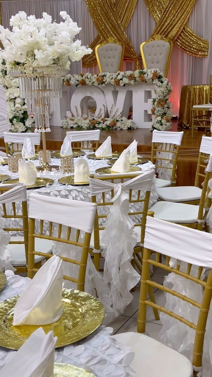 Gold charger plates and chairs at a wedding table with white floral centerpieces.