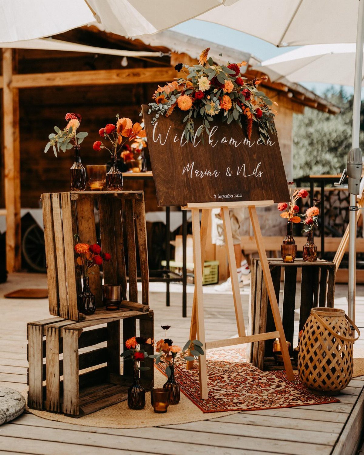 Wooden welcome sign with autumn flowers and rustic crates on a wooden deck