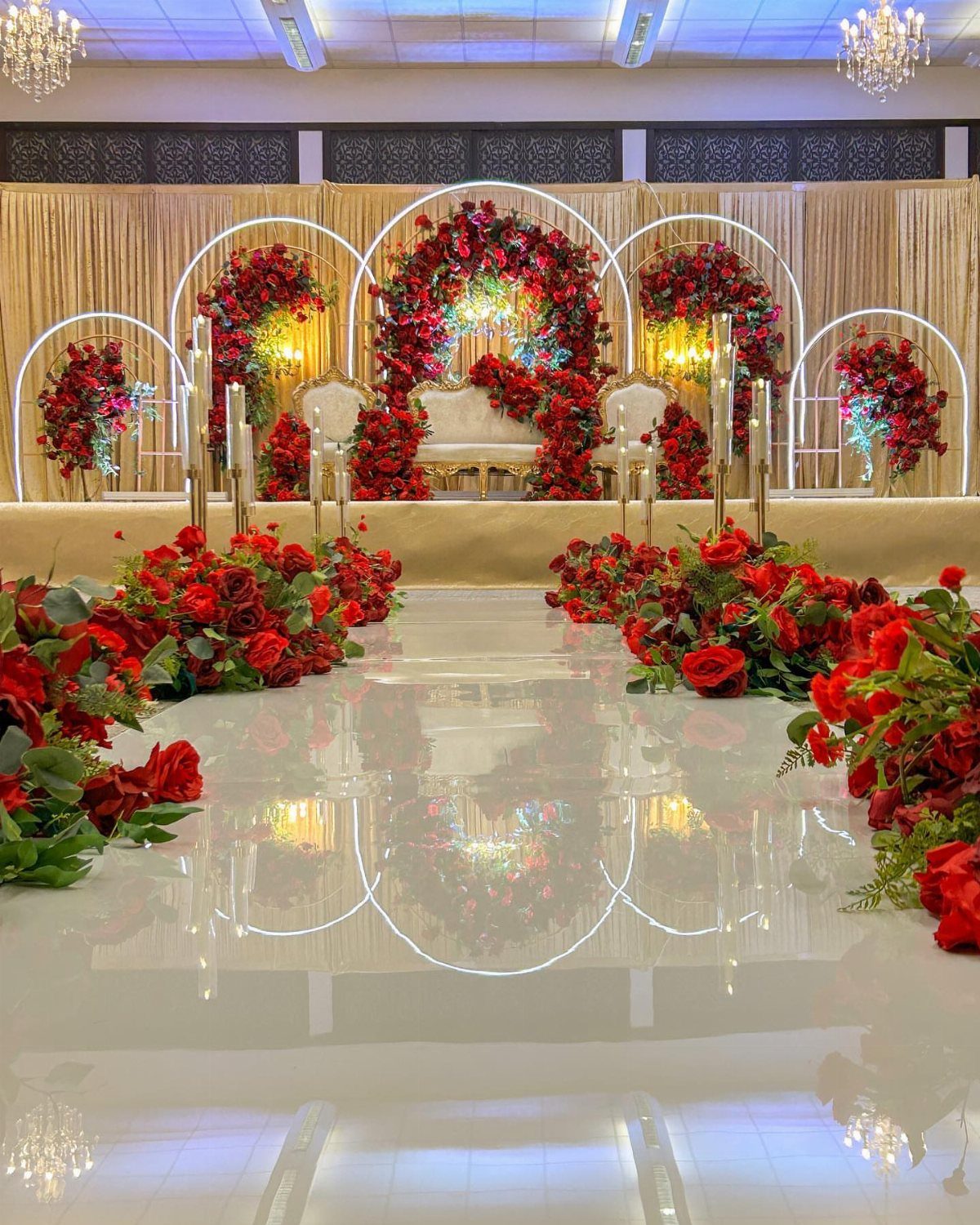 Red floral arches and rose-lined aisle in a luxurious wedding venue setting