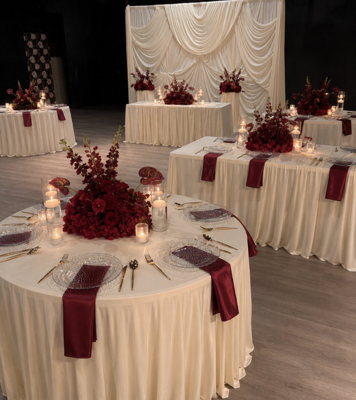 Cream wedding tables with red napkins, red floral centerpieces, and white candles.