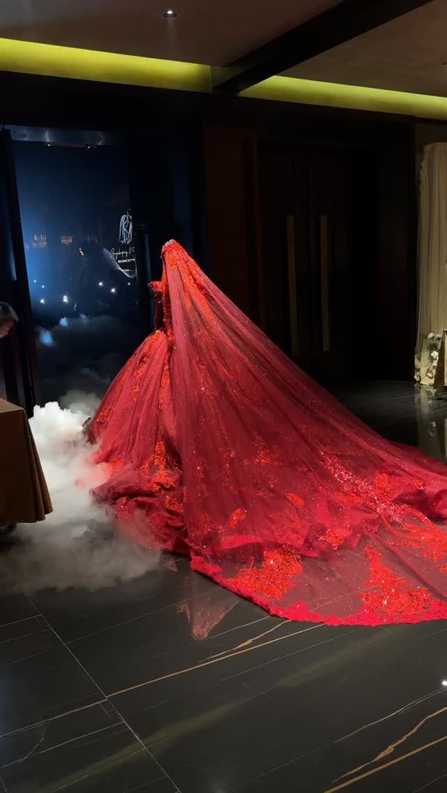 Red wedding gown with a long lace train surrounded by white fog.