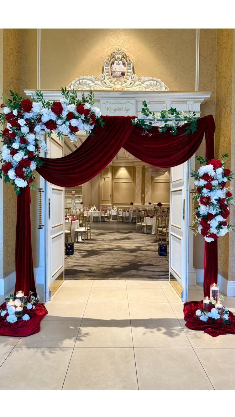 Red and white floral arrangements with red velvet draping framing a ballroom entrance