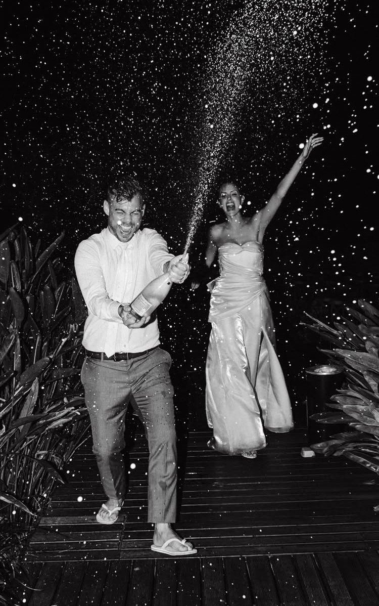 Couple celebrating at night with a large spray of champagne from a bottle.