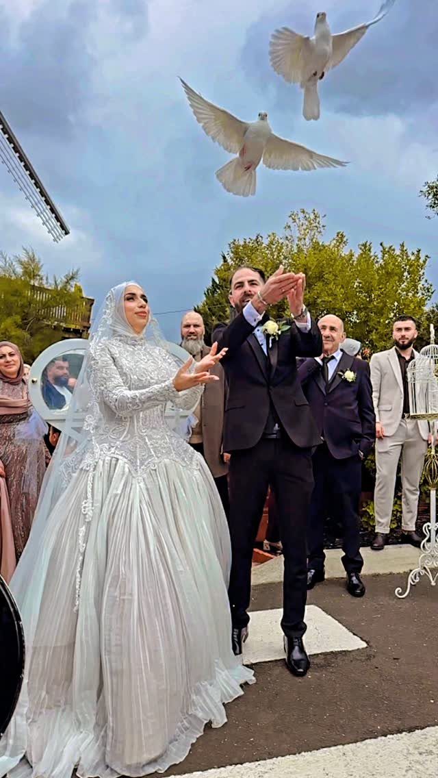 Bride and groom releasing two white doves during an outdoor wedding celebration.