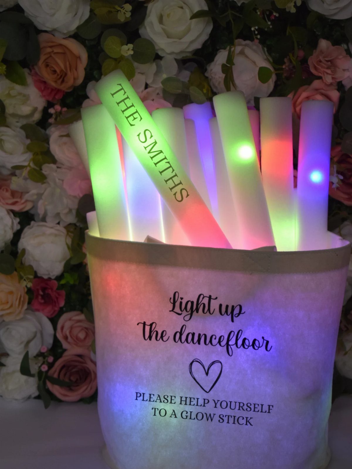 Glowing neon sticks in a white bucket against a floral rose background.