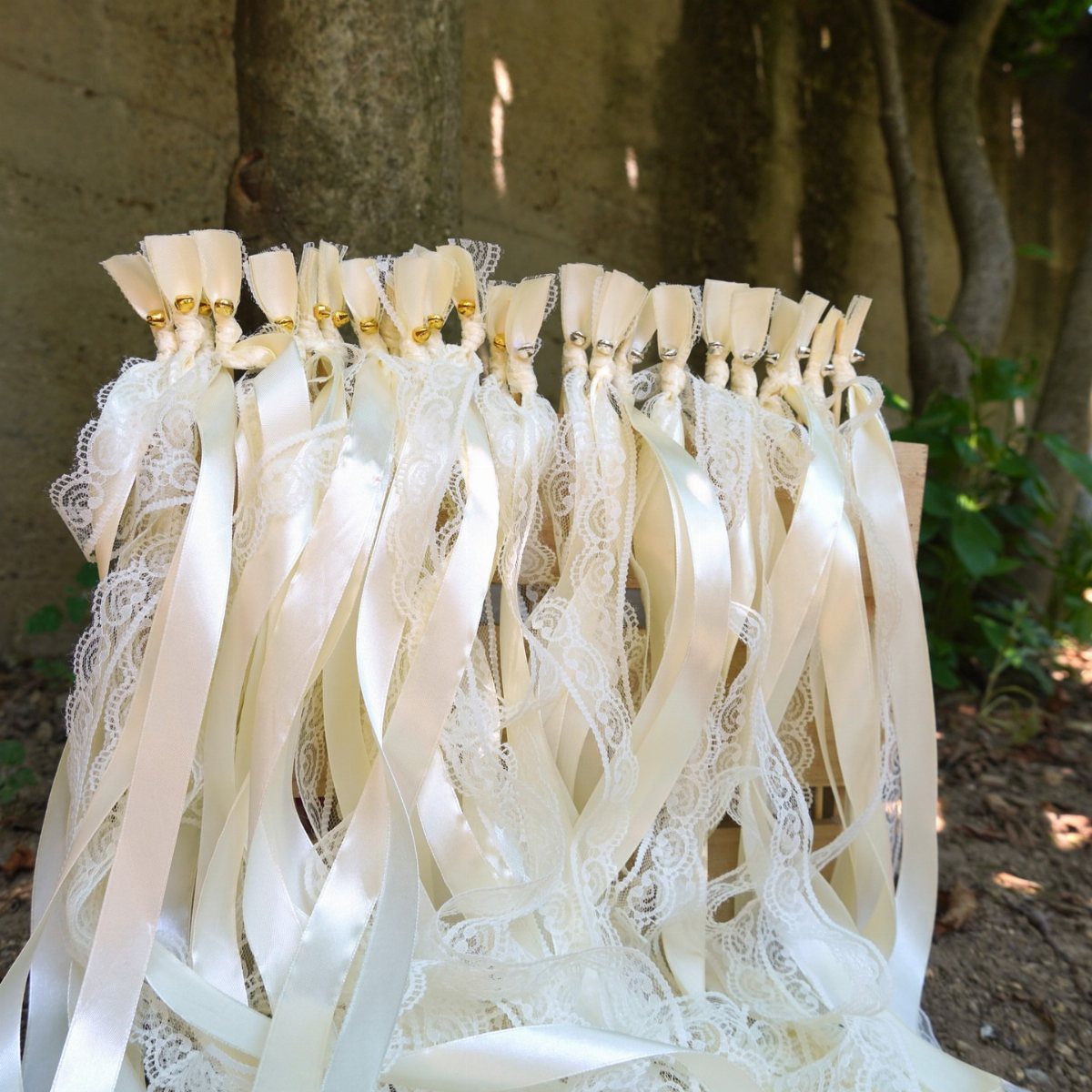 White and cream ribbon wands with lace and satin ribbons gathered outdoors.