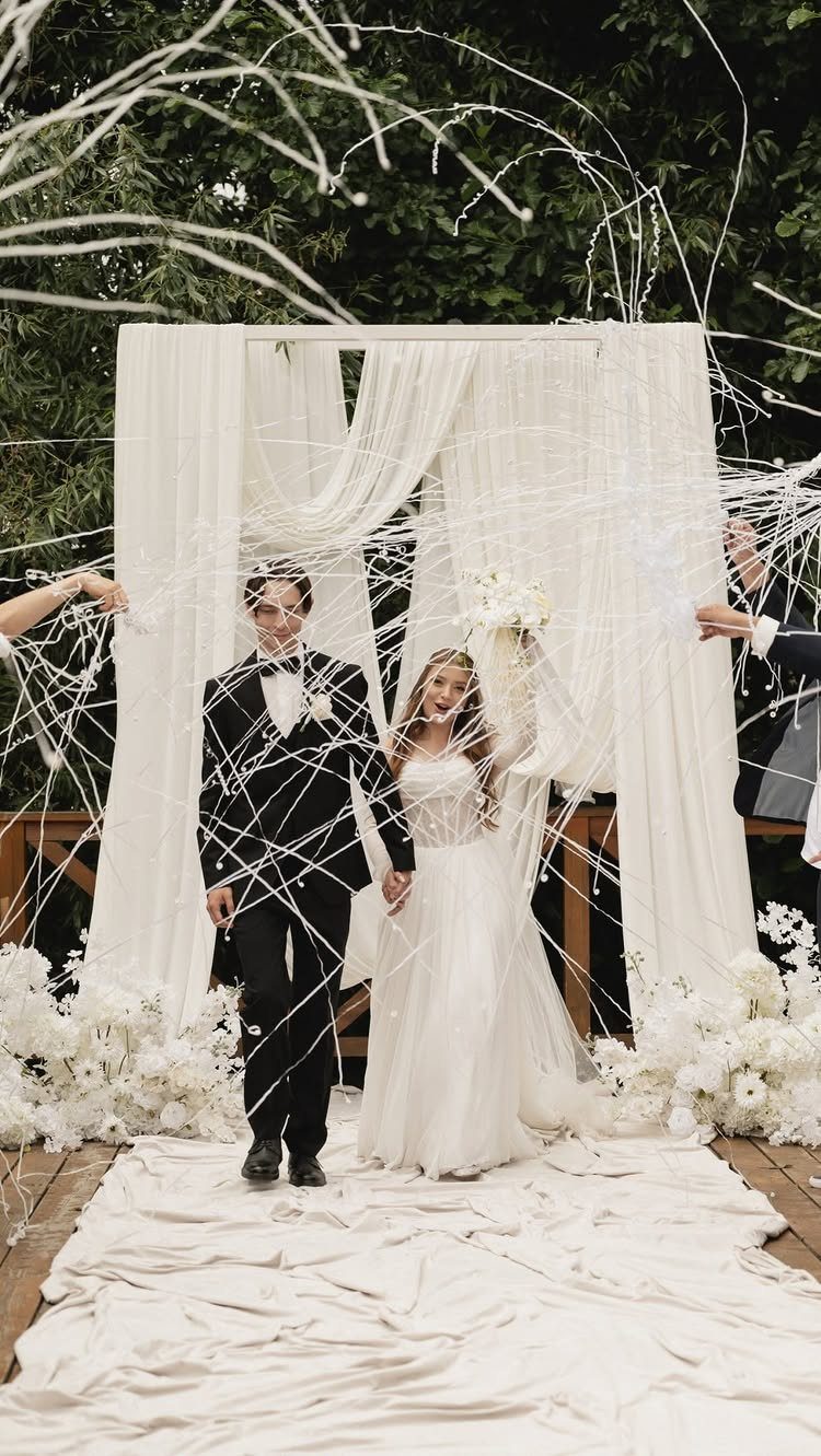 Bride and groom walking through a web of white silly string at wedding