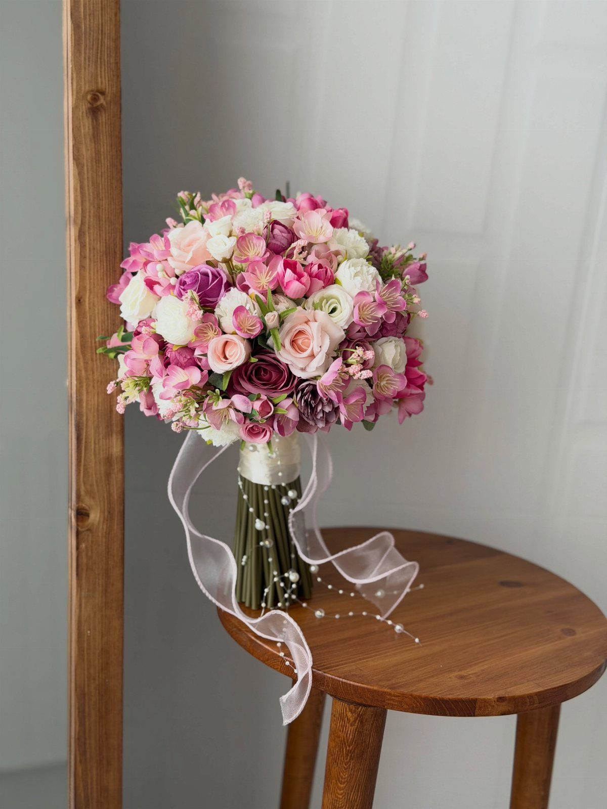 Round wedding bouquet with pink and white flowers on a wooden stool