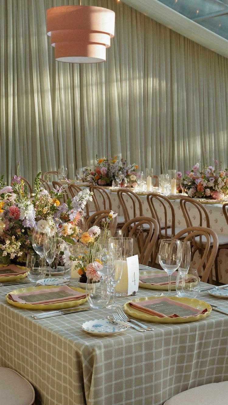 Checkered table linens on a wedding table with gold plates and floral centerpieces.