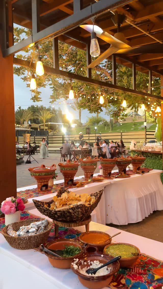 Nacho bar buffet with tortilla chips and salsas under a lit pergola.