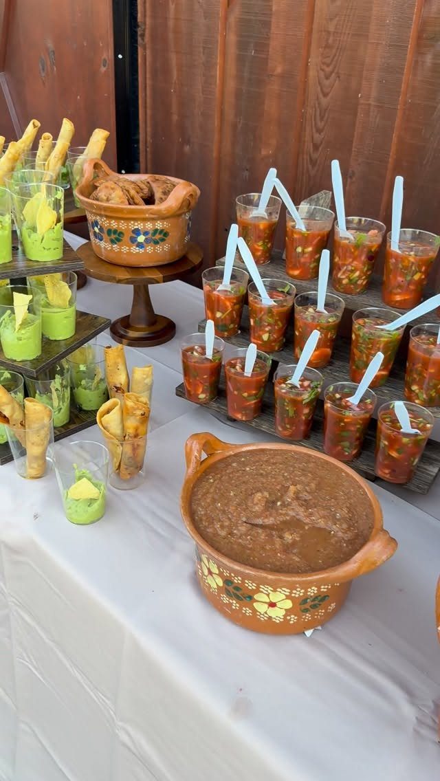Mexican food catering spread with salsa cups, guacamole, beans, and tortilla chips.