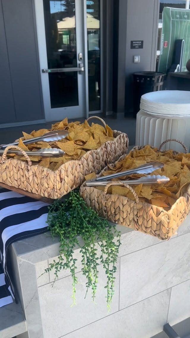 Tortilla chips in woven wicker baskets with silver tongs on a stone ledge