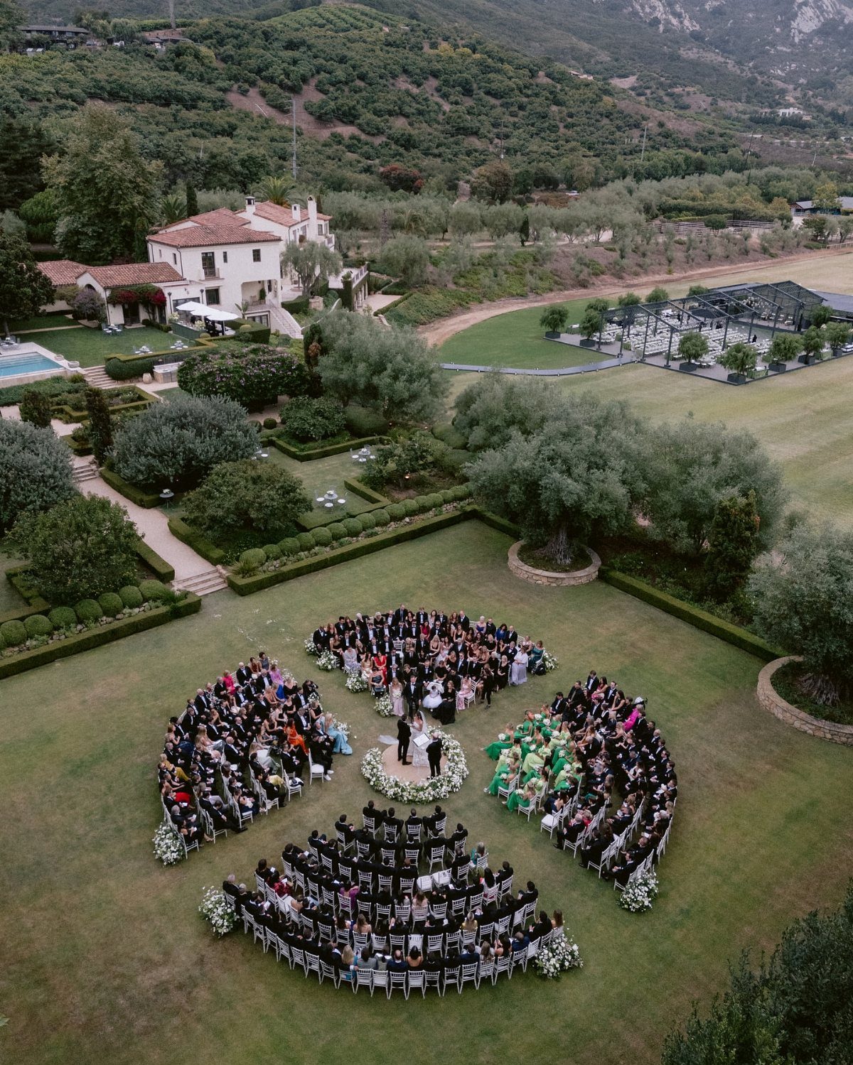 Circular seating arrangement for a wedding ceremony on a lush green estate lawn.