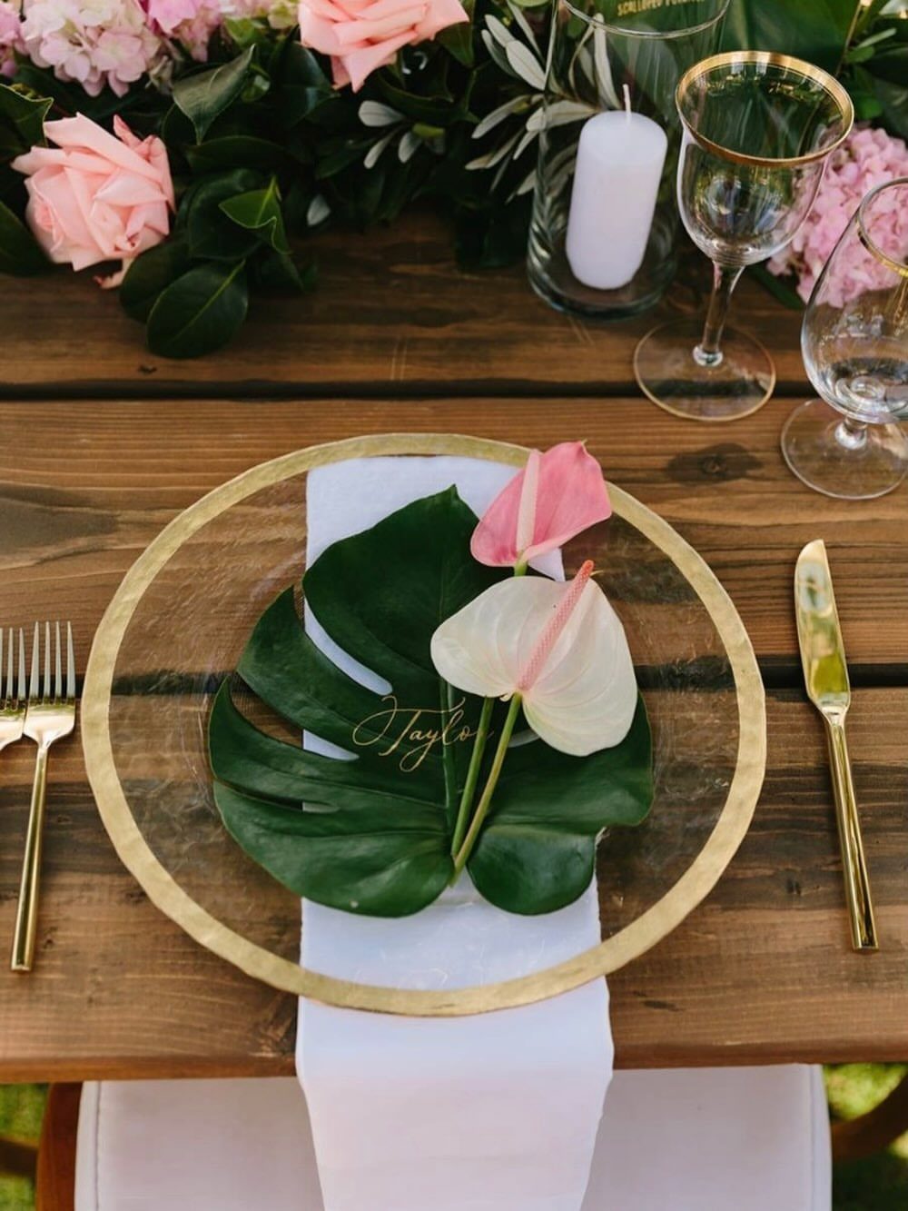 Monstera leaf place card with gold calligraphy on a gold charger plate.
