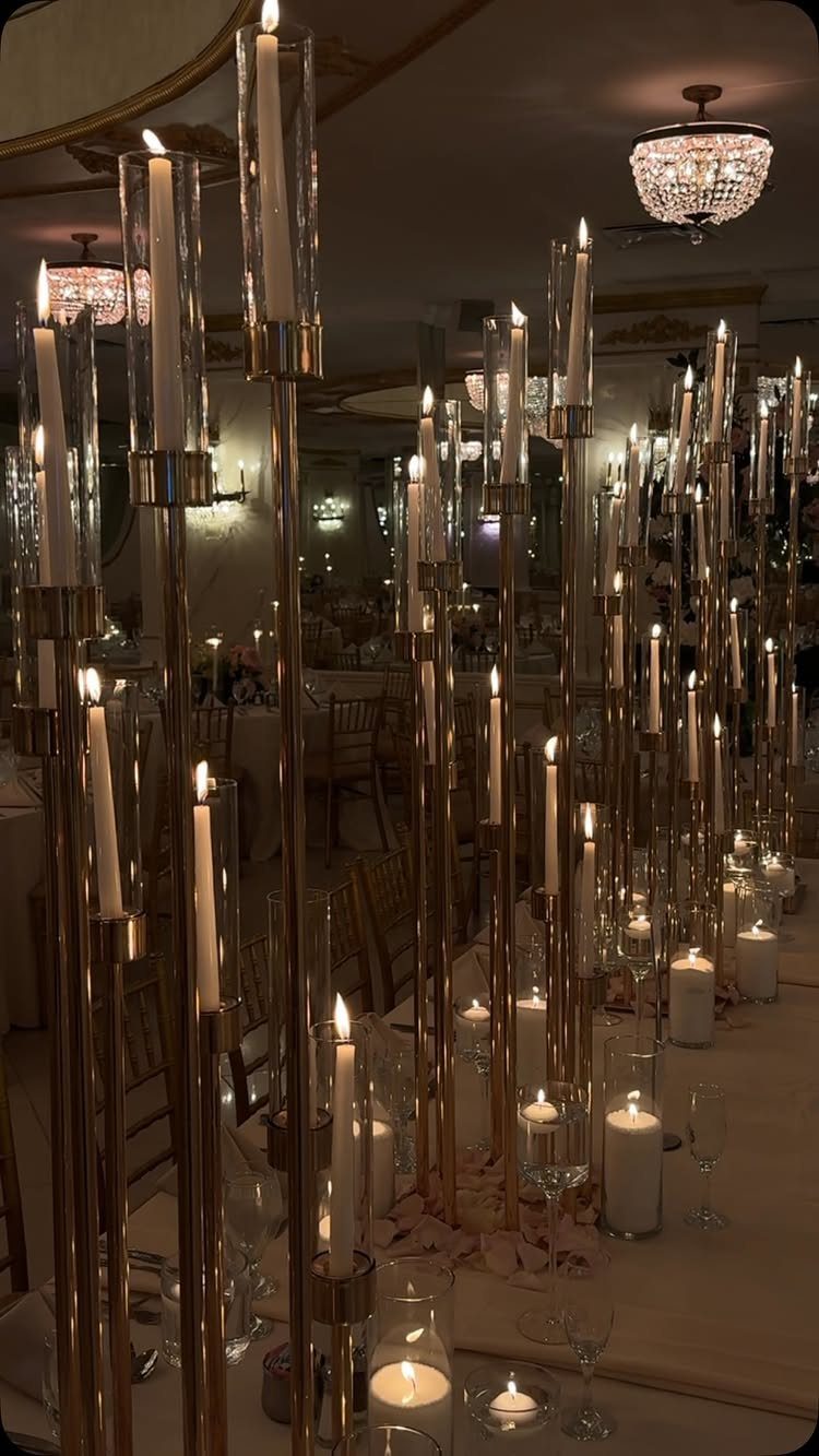 Tall gold candle holders with white taper candles as wedding table centerpieces.