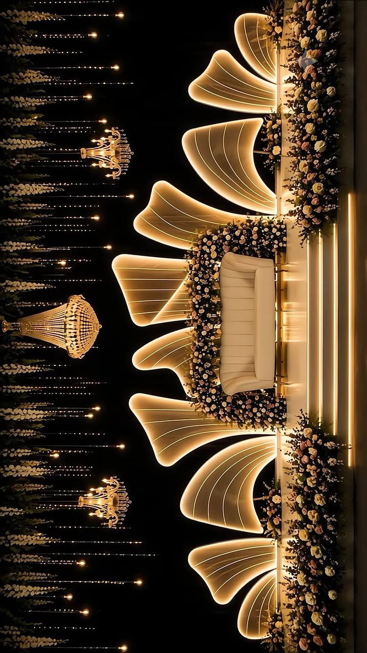 Luxurious event stage with glowing curved light installations, chandeliers, and floral arrangements.