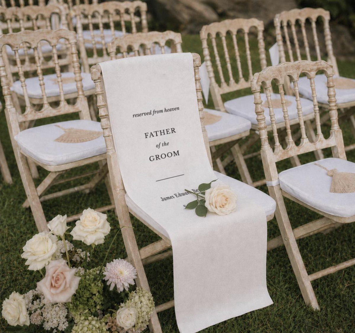 White wedding chairs on grass with a memorial drape for the groom's father.