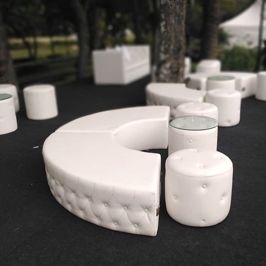 White tufted lounge furniture and ottomans arranged for open seating outdoors.