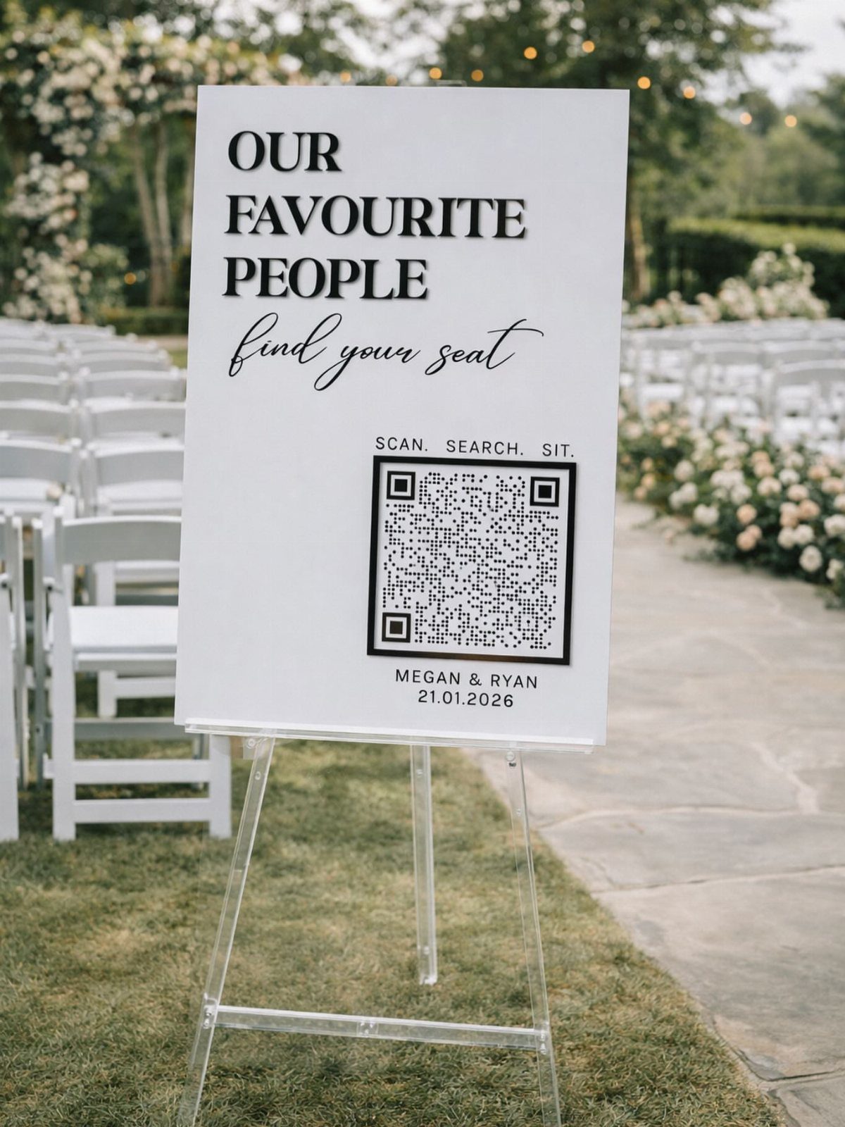 White wedding seating sign with QR code on a clear acrylic easel outdoors.