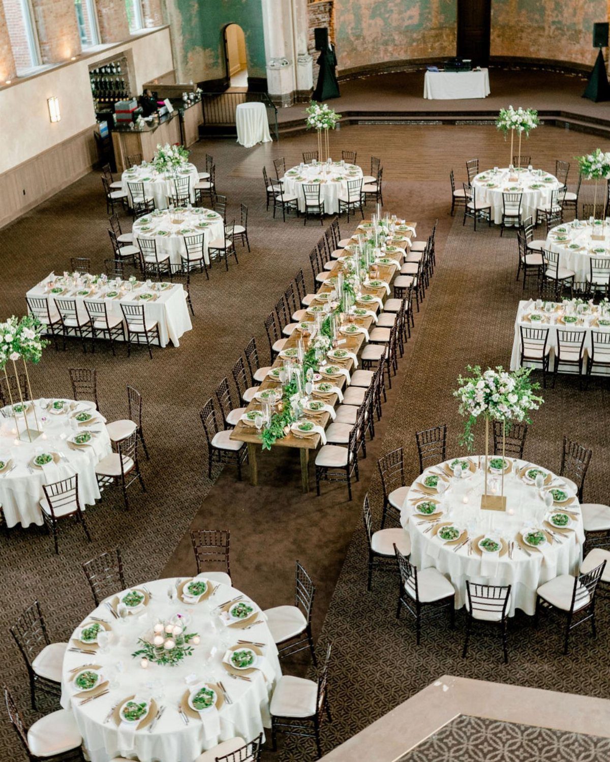 Round and rectangular wedding reception tables with white linens and floral centerpieces.