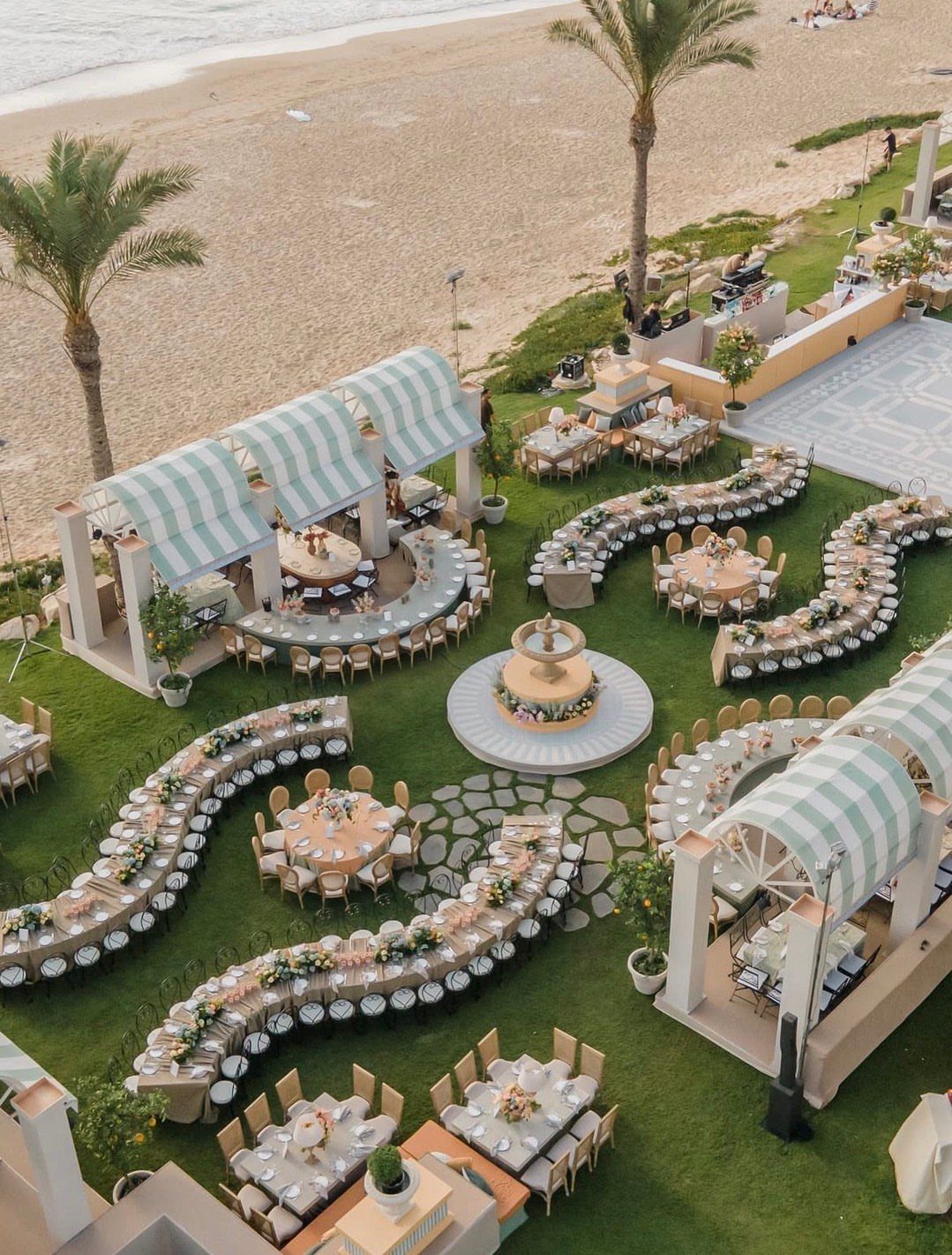 Outdoor wedding reception with curved and round tables on a lawn by the beach.