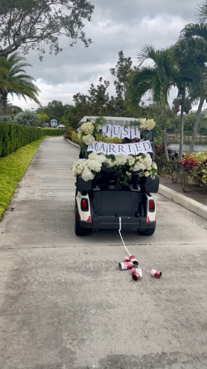 White golf cart decorated with flowers and just married sign on a path