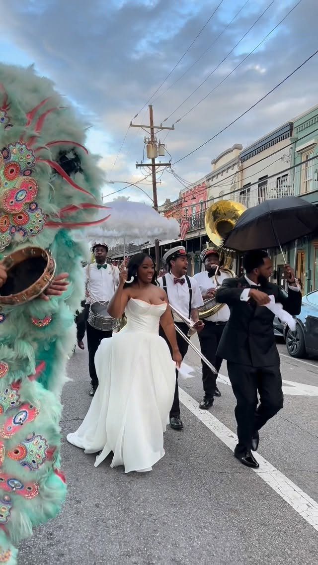 Bride and groom leading a festive second line parade with a brass band.