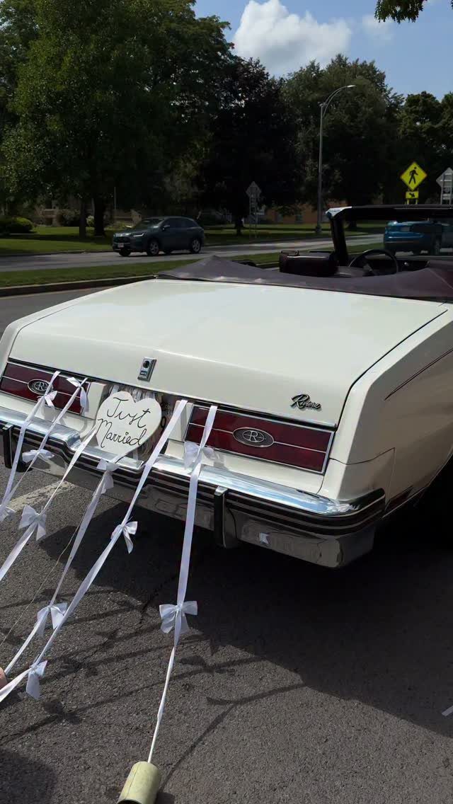 White vintage convertible car with Just Married sign and ribbons on the back.