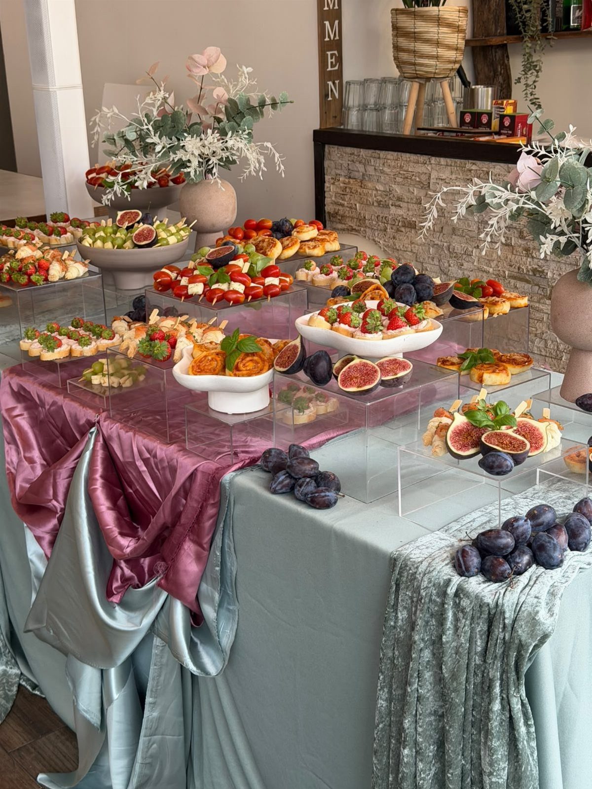 Bruschetta bar with toasted bread, fresh figs, and grapes on satin tablecloths.