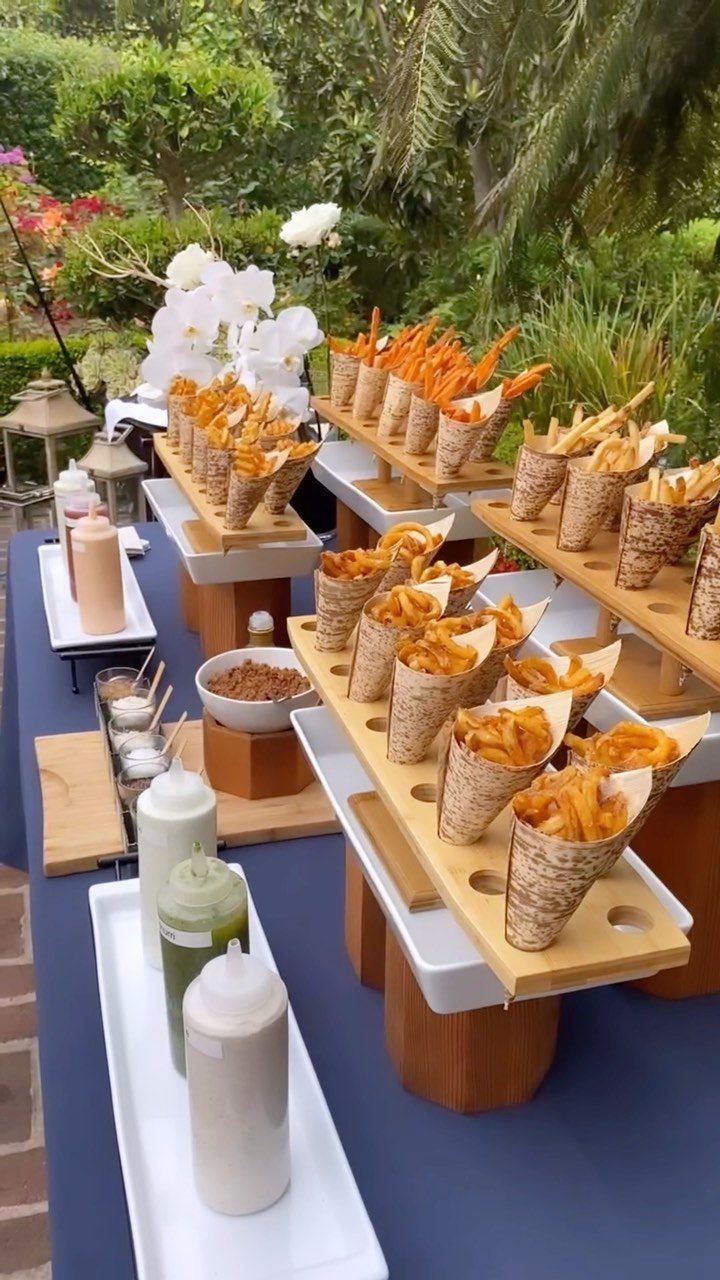 French fry bar with cones of fries and dipping sauces on a blue table.