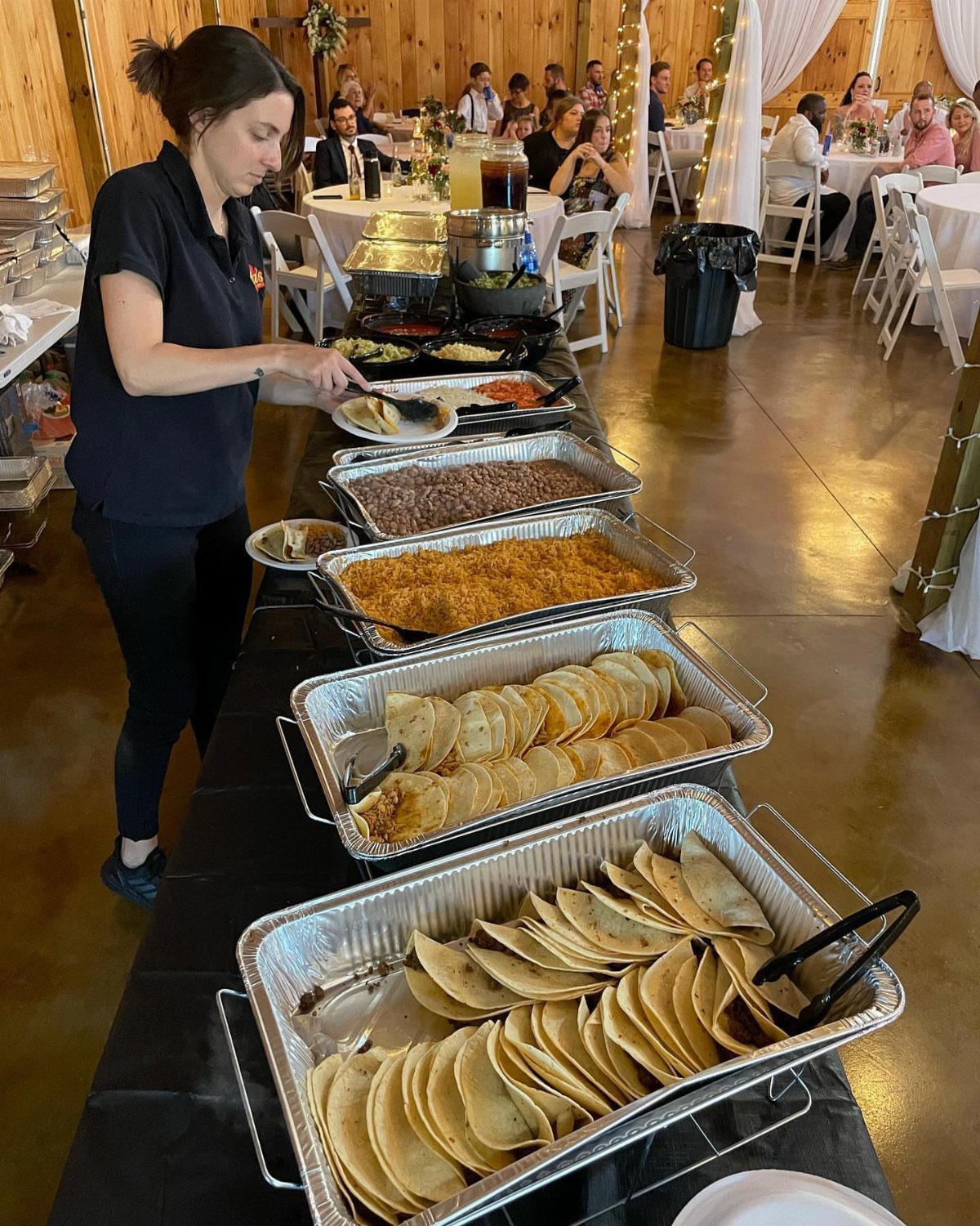 Taco bar with corn tortillas and meat in aluminum trays at a wedding.