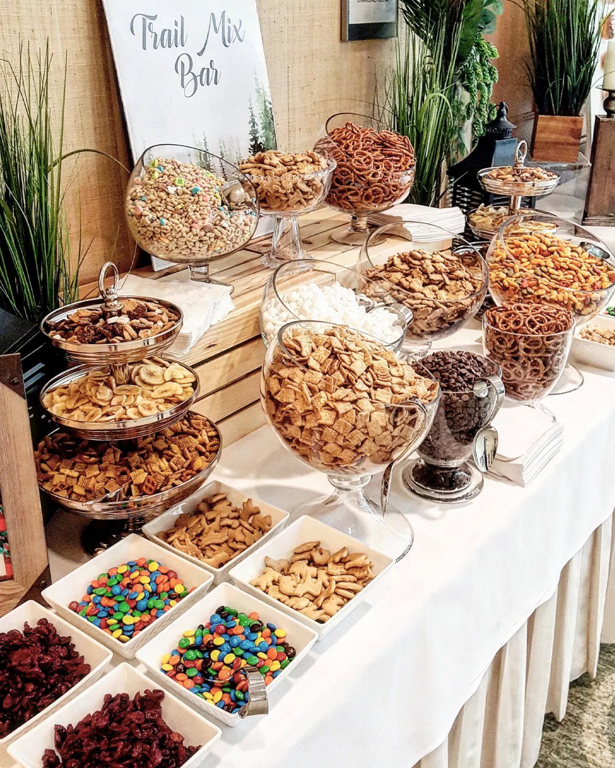 Trail mix bar with various bowls of nuts, candies, and pretzels on a table.