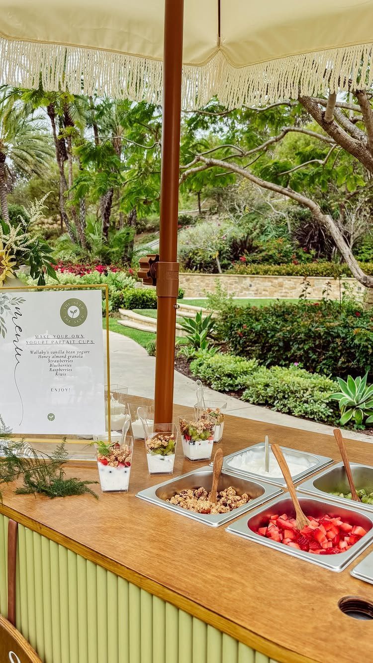 Yogurt parfait bar with fruit and granola on a wooden outdoor counter