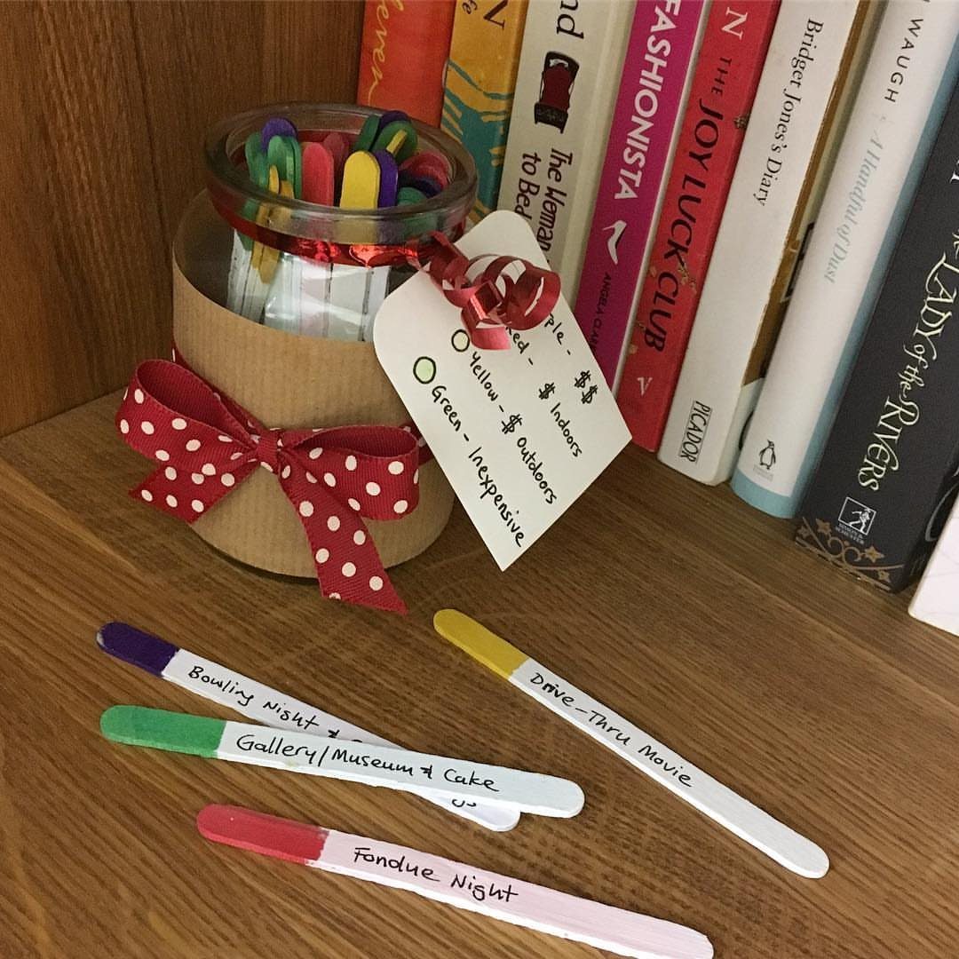 Colored popsicle sticks with handwritten date ideas next to a decorated jar.
