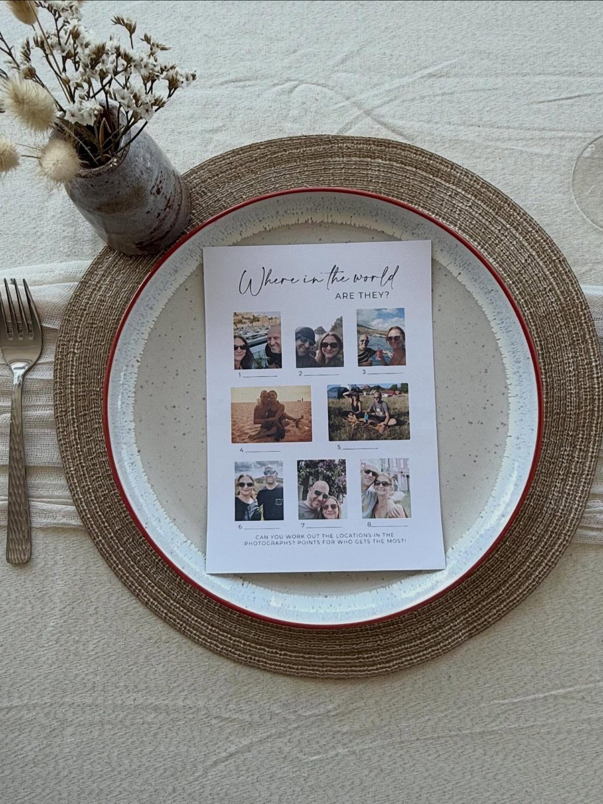Wedding table setting with a 'Where in the world' photo game on a plate.