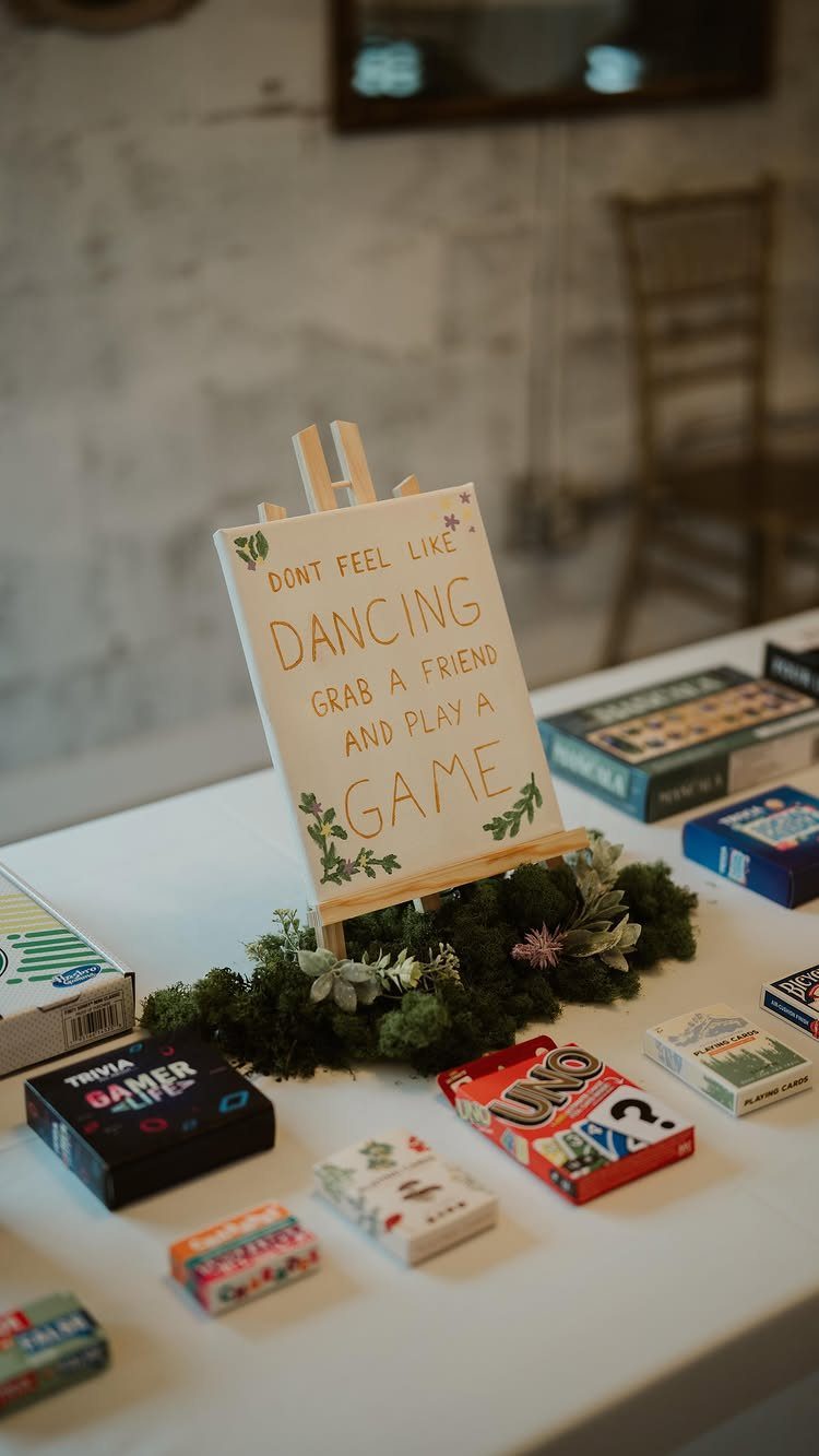 Board games and a sign on a white table at a wedding reception.