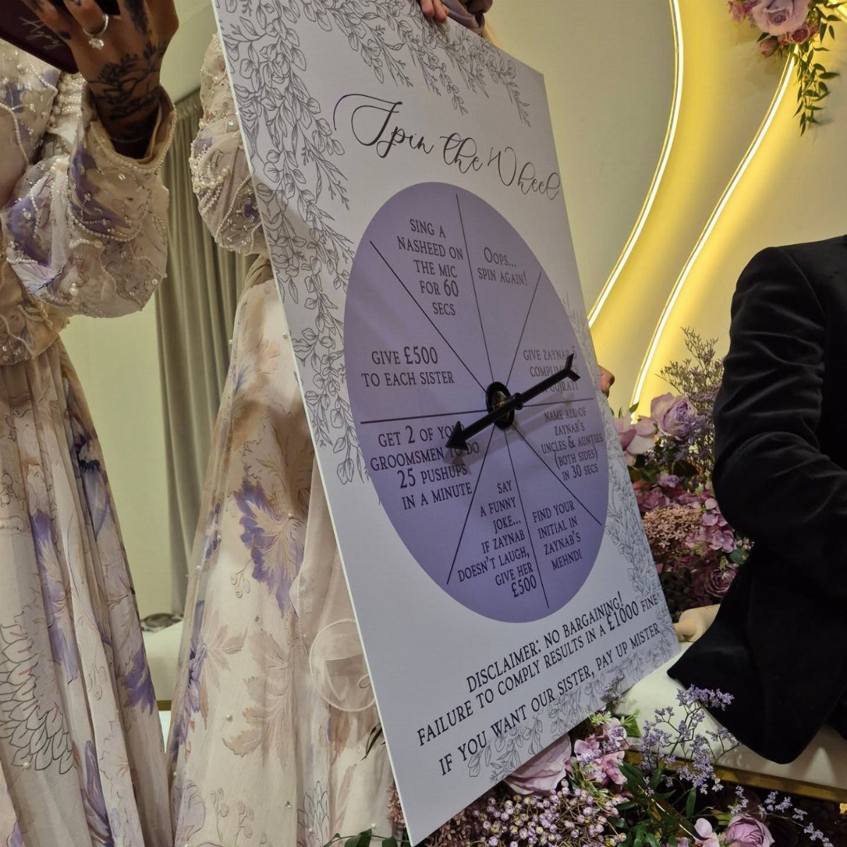 Prize wheel sign with challenges held by a person at a wedding event.