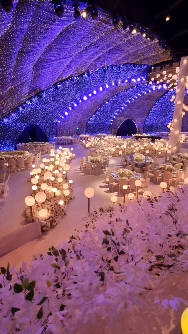 Curved ceiling covered in purple fairy lights over a luxury wedding reception setup