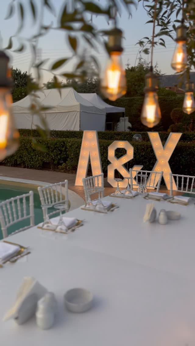Hanging Edison bulbs and large illuminated letters A and X at outdoor wedding
