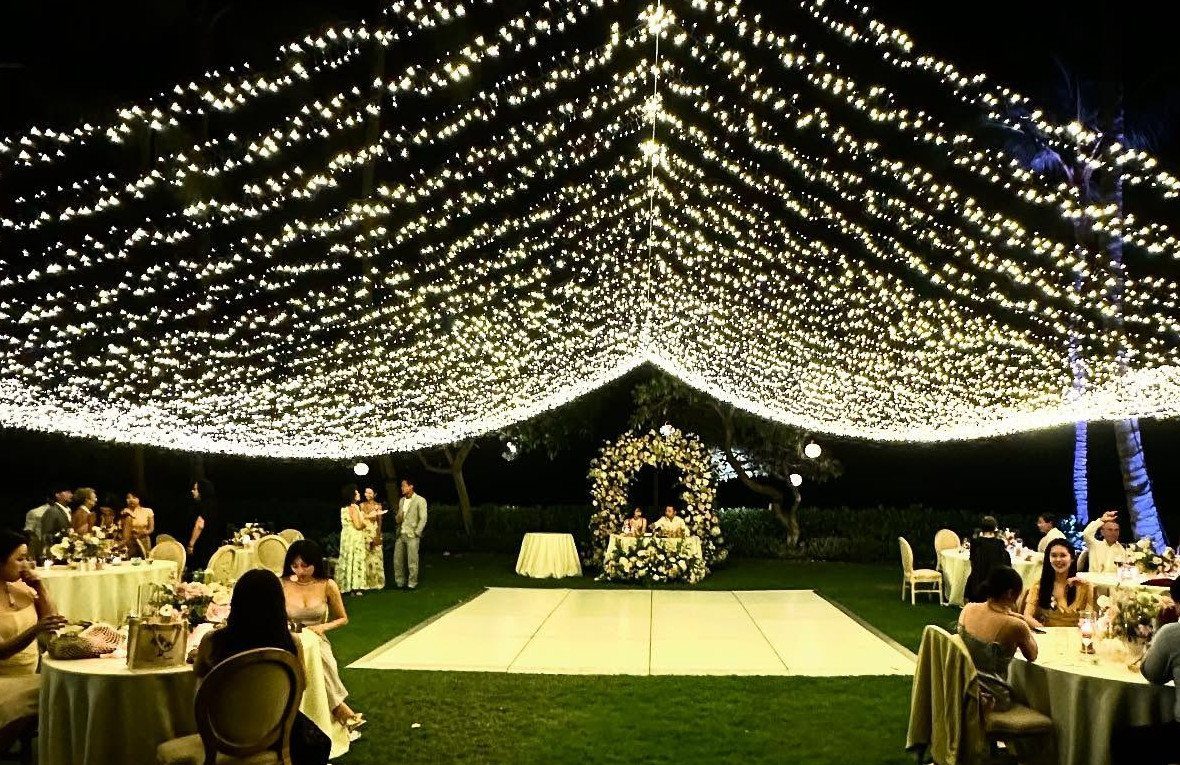 Warm white fairy light canopy over a white dance floor at night wedding