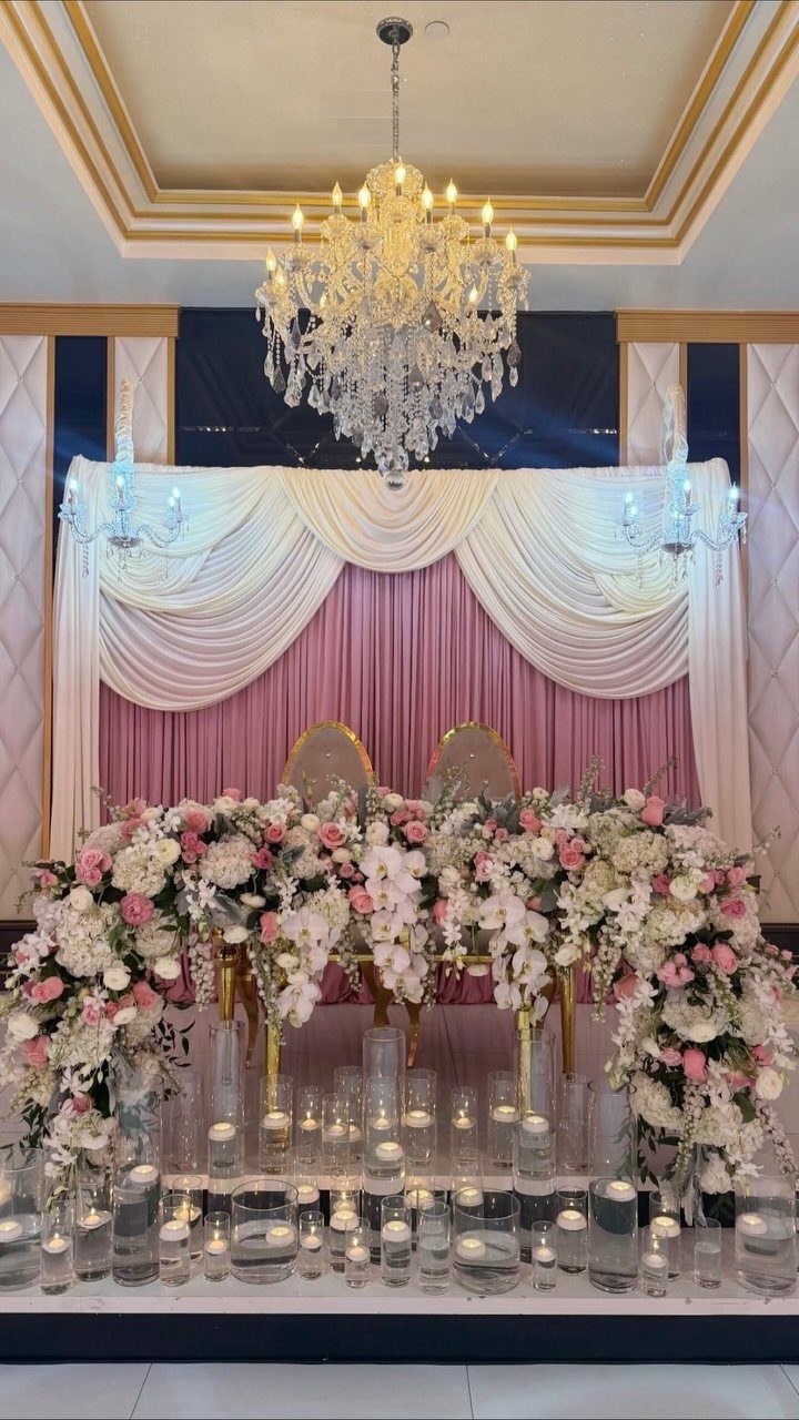 Wedding head table with pink and white floral arrangements and floating candles.