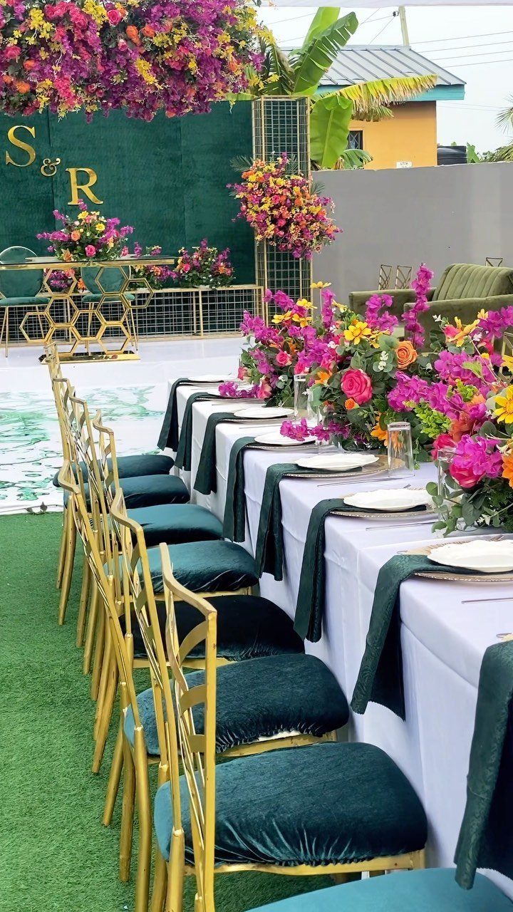 Emerald green and gold wedding table setting with vibrant pink floral centerpieces.