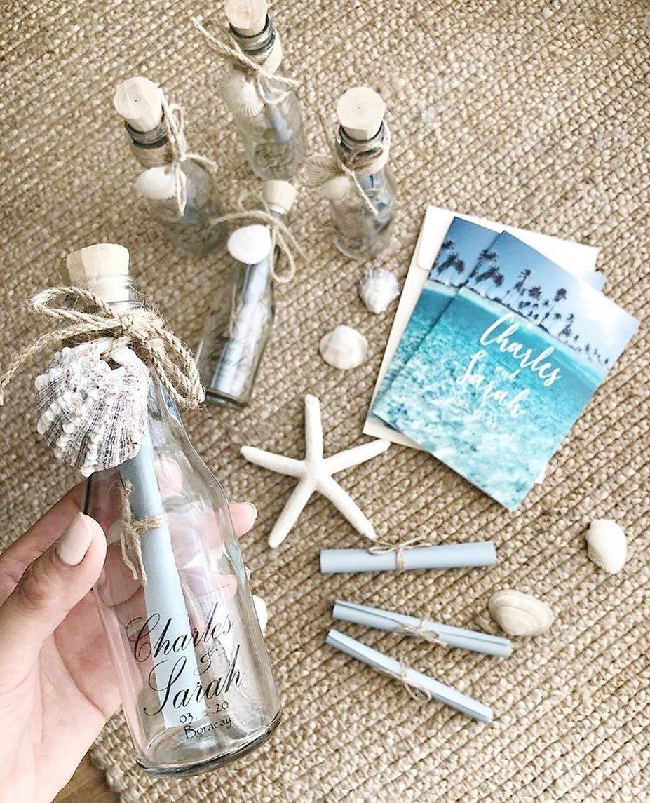 Glass bottles with rolled scrolls and seashells on a woven beach mat.