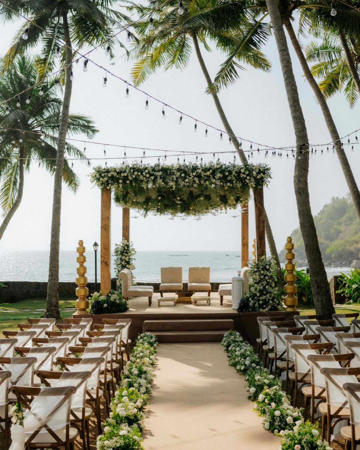 Wooden wedding altar with white flowers on a beach with palm trees.