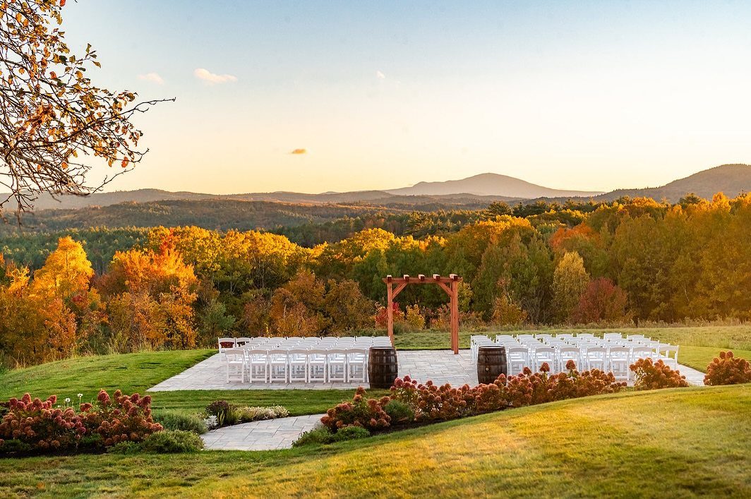 Outdoor wedding ceremony setup overlooking a valley of colorful autumn foliage and mountains.