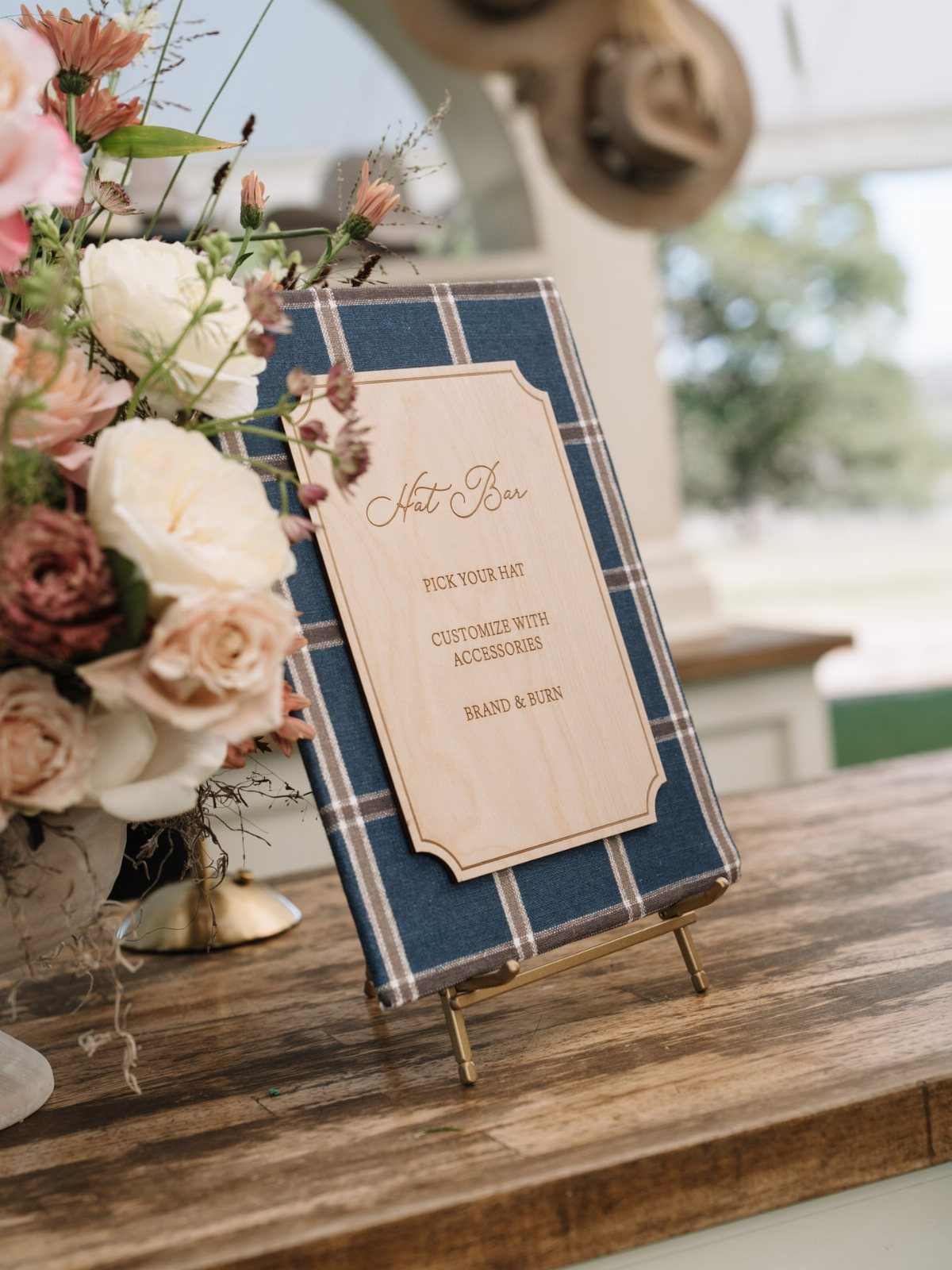 Floral arrangement and a Hat Bar sign on a rustic wooden table.