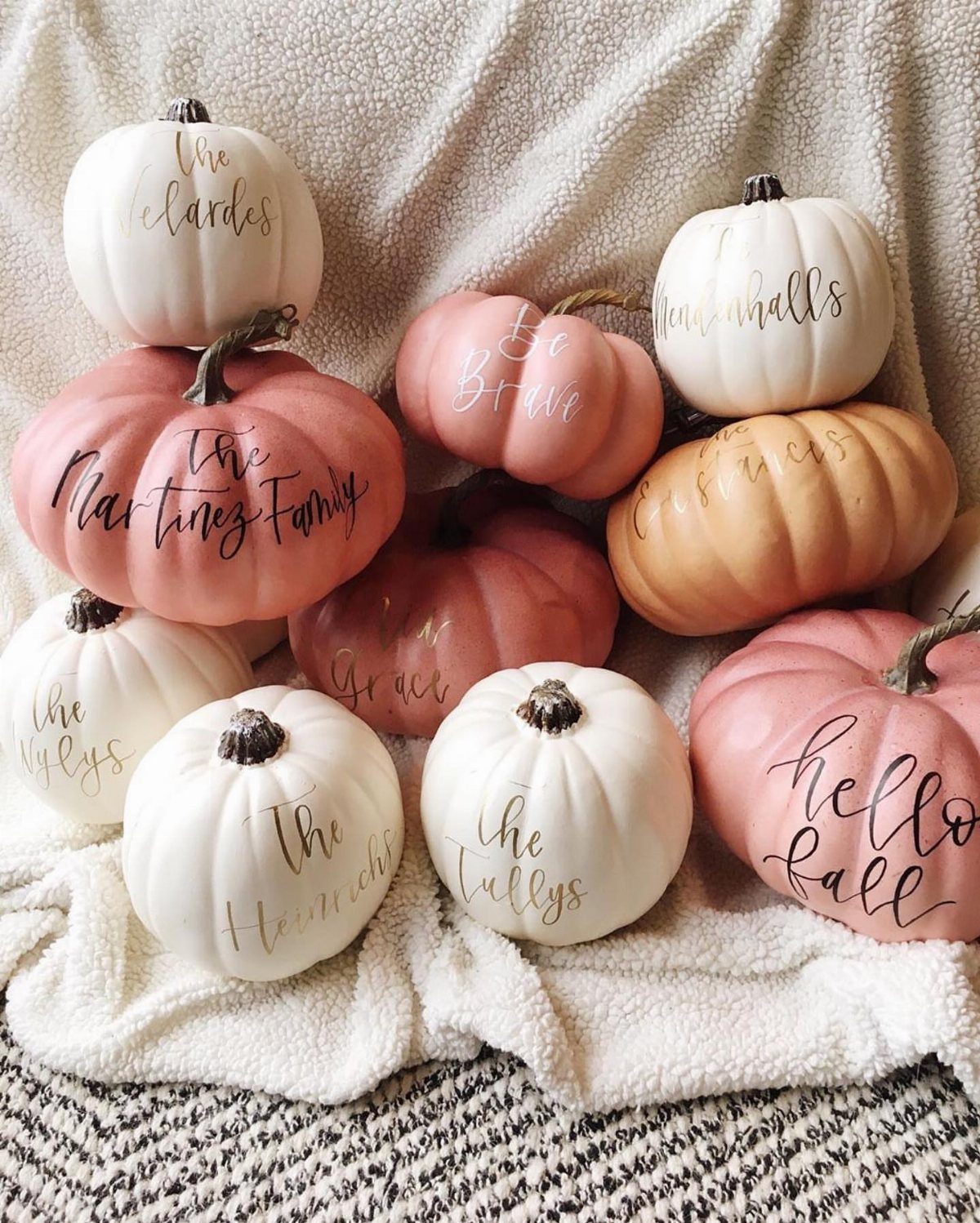 Painted pumpkins in white and peach tones with gold calligraphy on a blanket