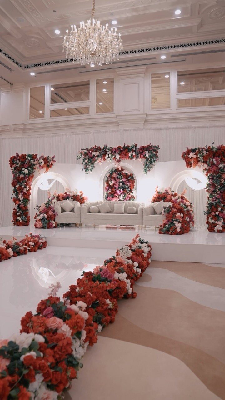 Wedding stage with white sofa and lush red and pink floral arrangements